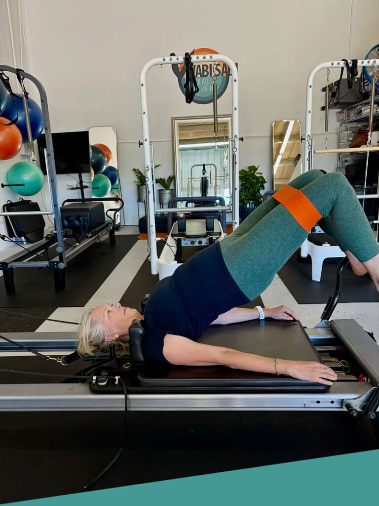 A client performing a bridge on the Reformer at Wabi-Sabi Pilates studio in North Boulder